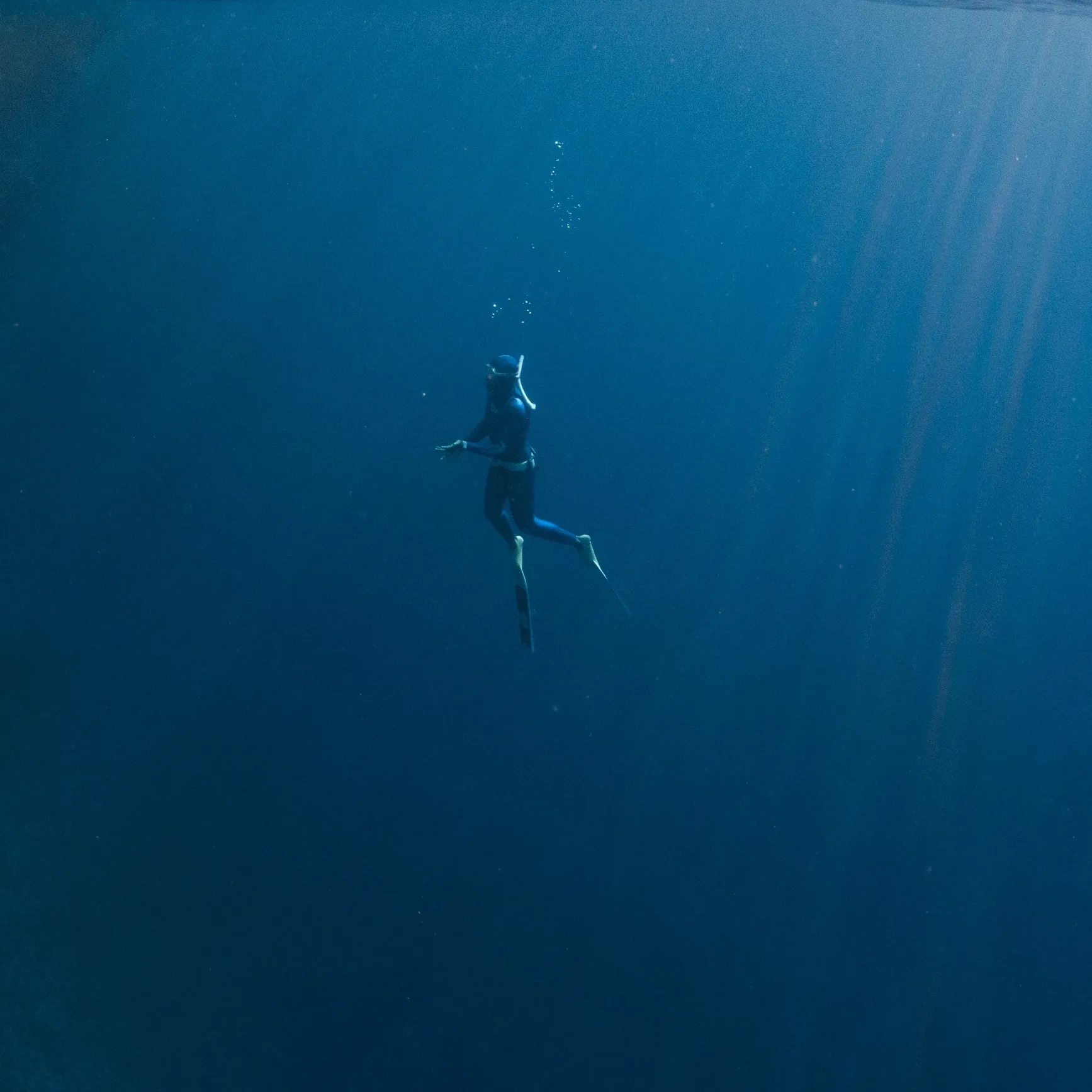 Freediver descending in deep blue water